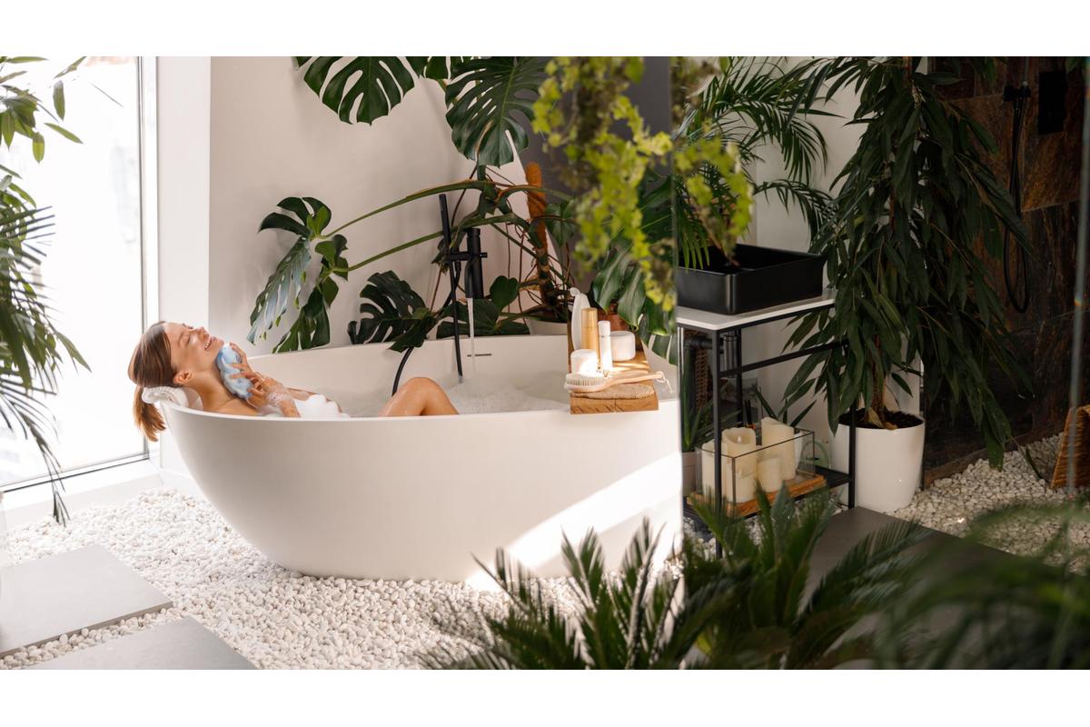Sauna domestica trasformata in oasi estiva con piante, luci soffuse e teli colorati.